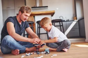 father and son playing with small toys on floor