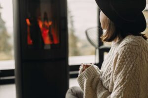 woman in hat and sweater near fireplace