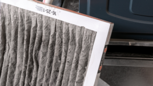 Used HVAC filter in front of an HVAC machine. The Importance of Furnace Cleaning and Maintenance