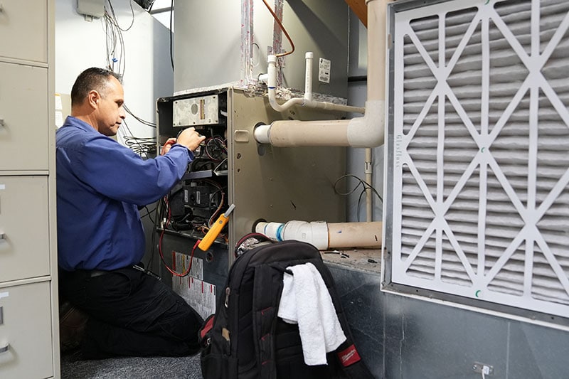 Is Your Heating System Ready for California Winter? A technician working on a furnace.