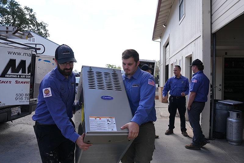 Two Maki technicians carrying new furnace.