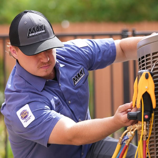 Maki Heating & Air Conditioning technician working on air conditioning unit