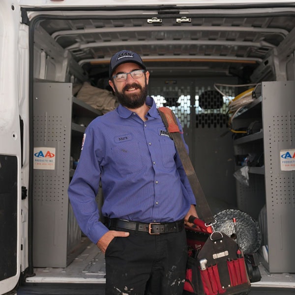 Maki Heating & Air Conditioning technician smiling with tool bag in front of work truck