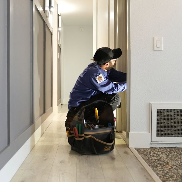 Maki Heating & Air Conditioning technician inspecting an air handler inside a wall
