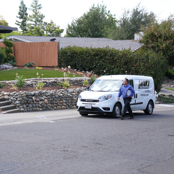 Maki Heating & Air Conditioning technician walking past work van towards customer’s home
