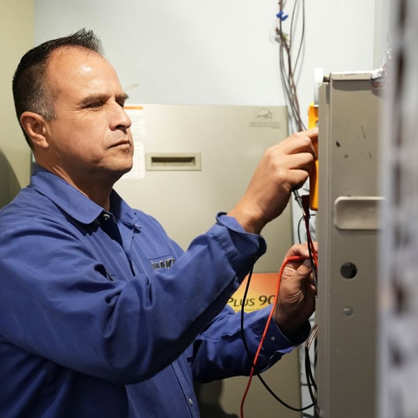 Maki Heating & Air Conditioning technician working on inside heating unit