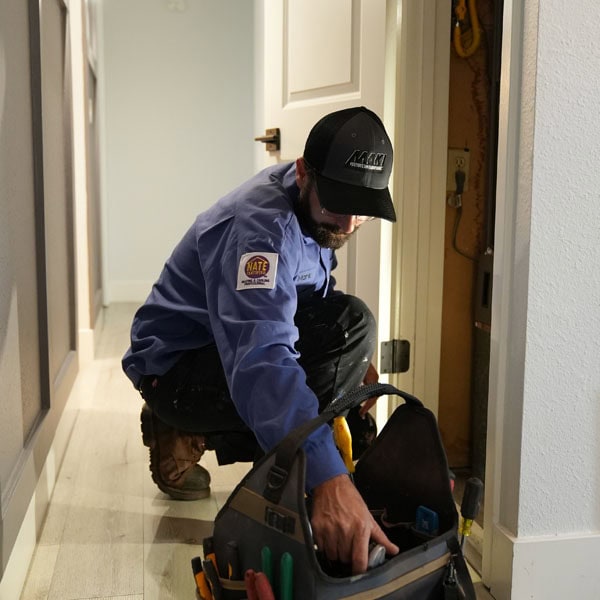 Maki Heating & Air Conditioning technician reaching for a tool inside tool bag