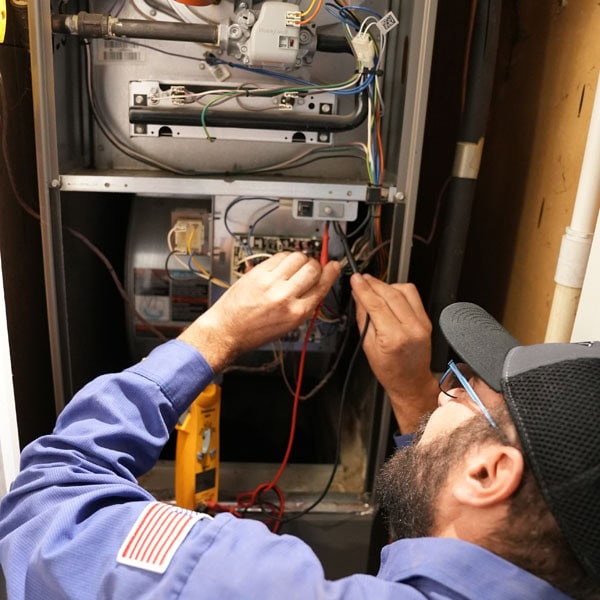 Maki Heating & Air Conditioning technician working on inside heating unit