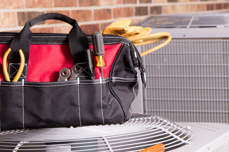 Fall HVAC Maintenance Tips to Prepare for Winter. Tools sitting on top of a heat pump.