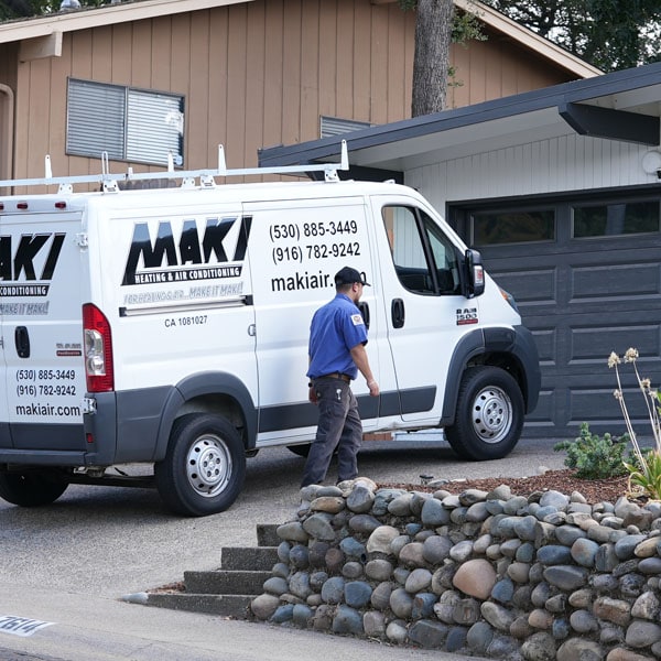 Maki Heating & Air Conditioning technician walking past truck towards a home
