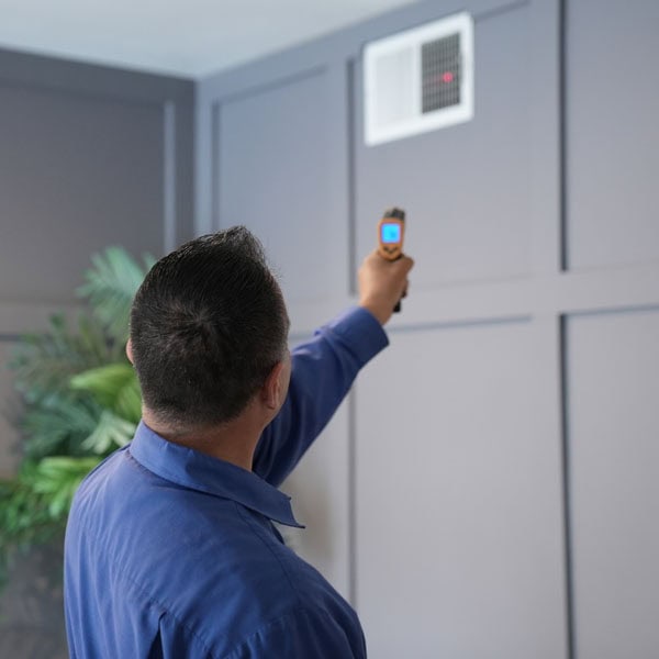 Maki Heating & Air Conditioning technician pointing infrared thermostat