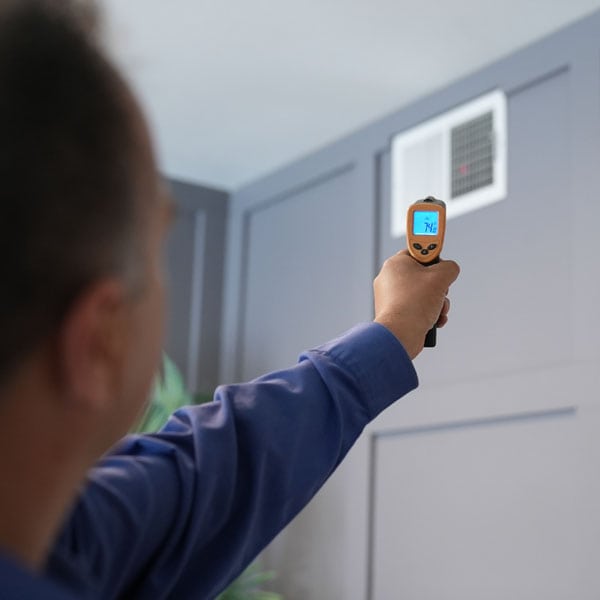 Maki Heating & Air Conditioning technician pointing infrared thermostat
